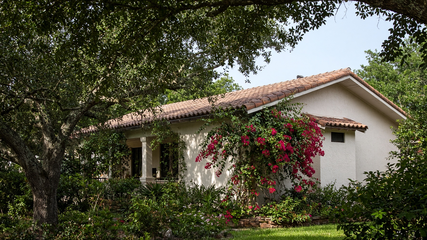 Low Florida house with a barrel-tile roof, stucco walls, and bougainvillea